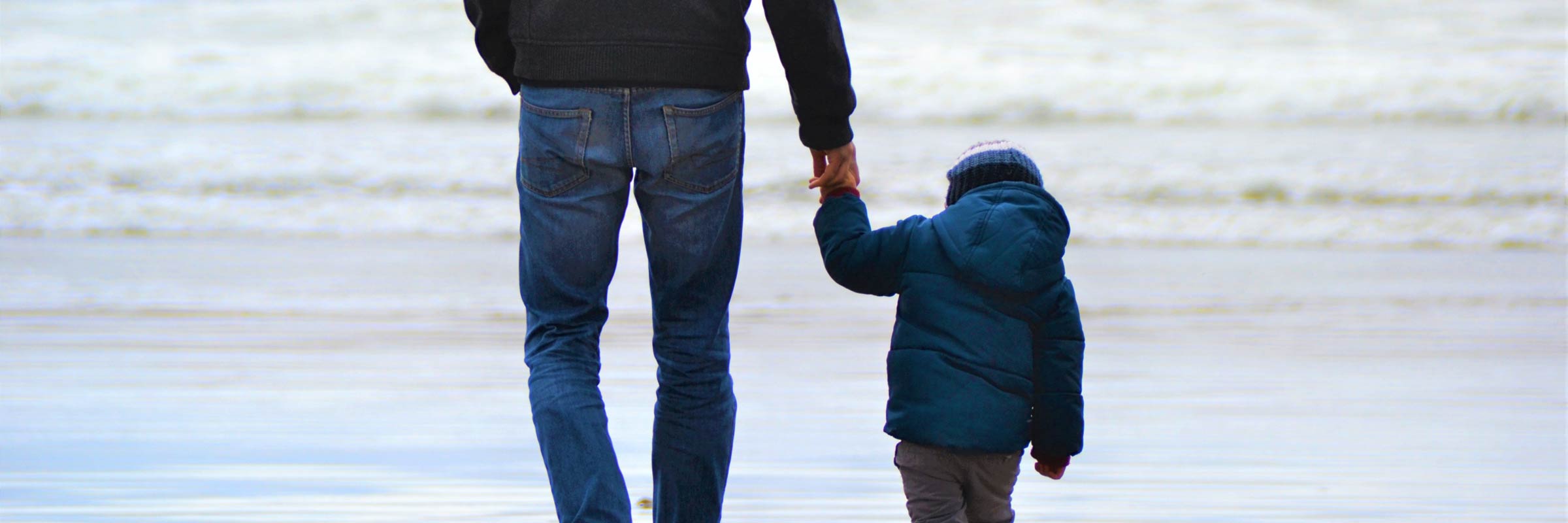 Un homme et un enfant se tiennent la main à la plage